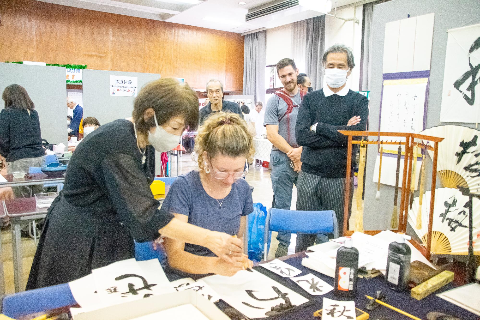 先生から習字を教わっている外国人女性の写真