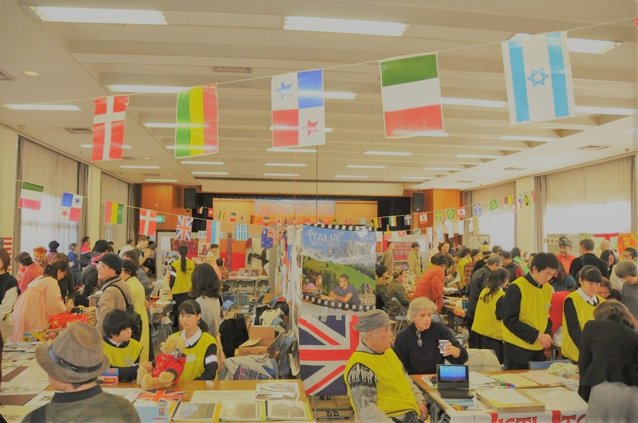 日本人市民と外国人市民が万国旗が飾られた会場で交流しているイベントの写真