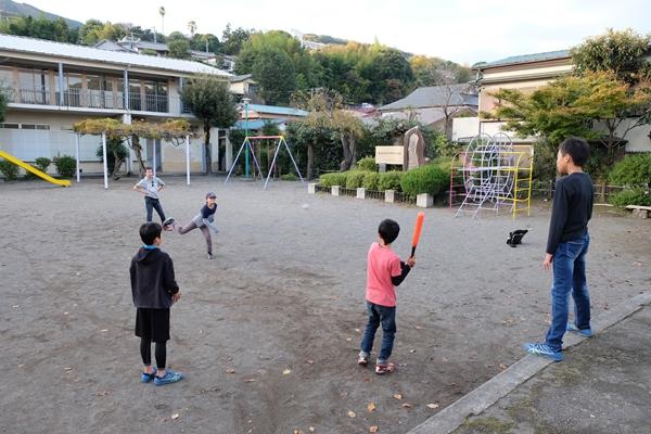 公園のオープンスペースで野球をする子供たちの写真