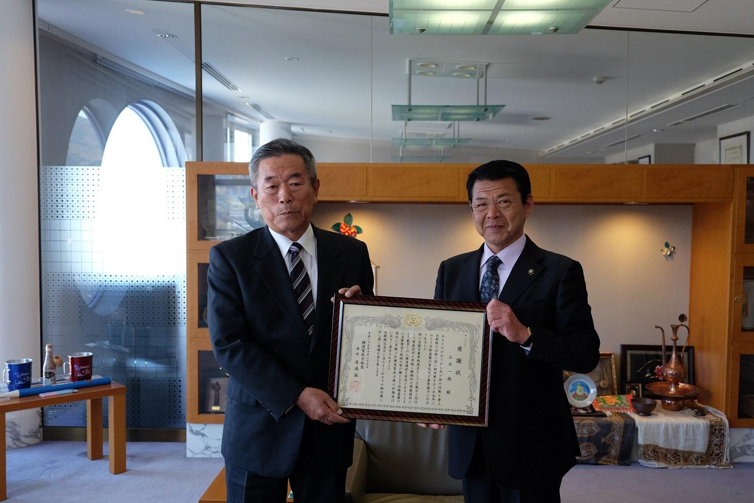 2017年12月5日石井一徳さんと市長の2人で感謝状を掲げる写真