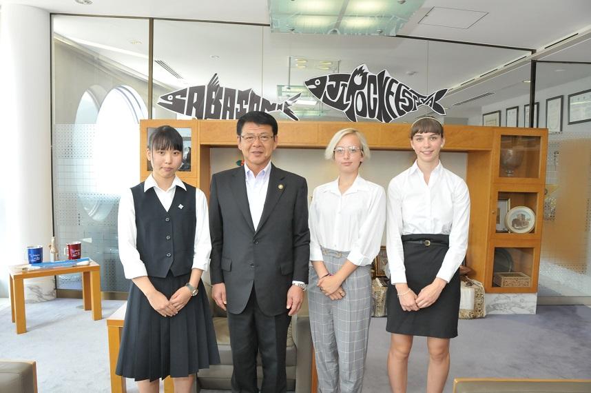 2018年8月3日 里吉凛香さんとメドウェイ学生2人との間に並ぶ市長の写真
