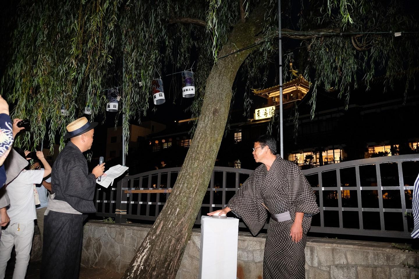 2018年8月6日 東海館を背景に点灯ボタンを押す市長の写真