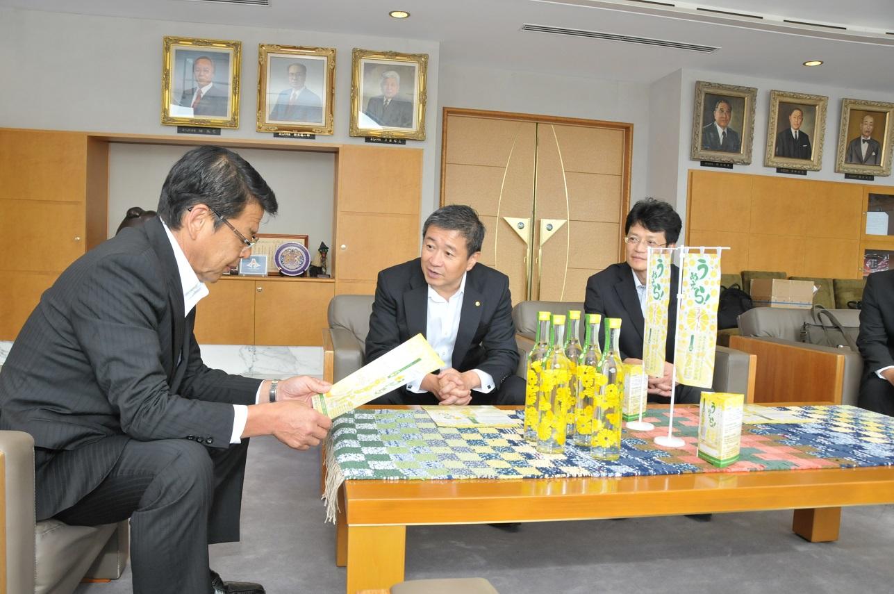 2018年8月7日 机に置かれた「うめえら！ライト」と早川弘之社長から報告を受ける市長の写真
