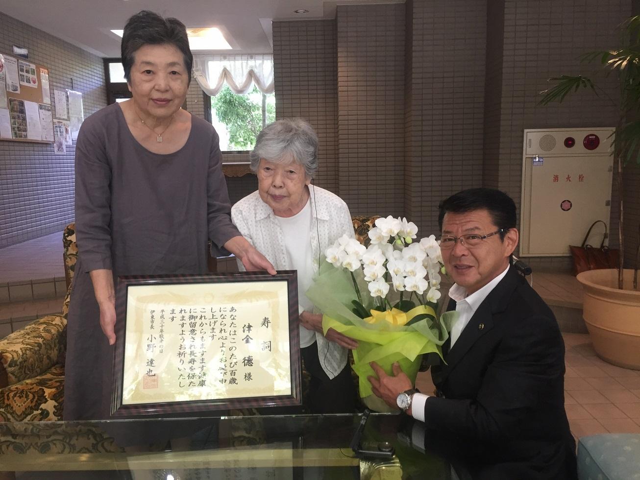 2018年9月12日 寿詞とコチョウランの鉢植えを贈る市長と受け取る津金徳さんの写真