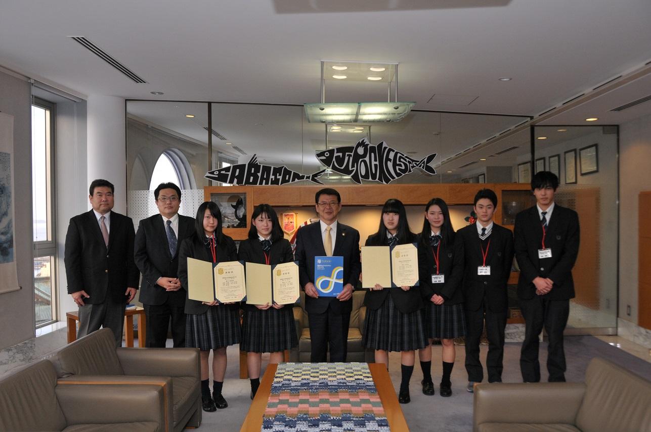 2019年1月16日表彰状を掲げる伊東商業高等学校の皆さんと並ぶ市長の写真