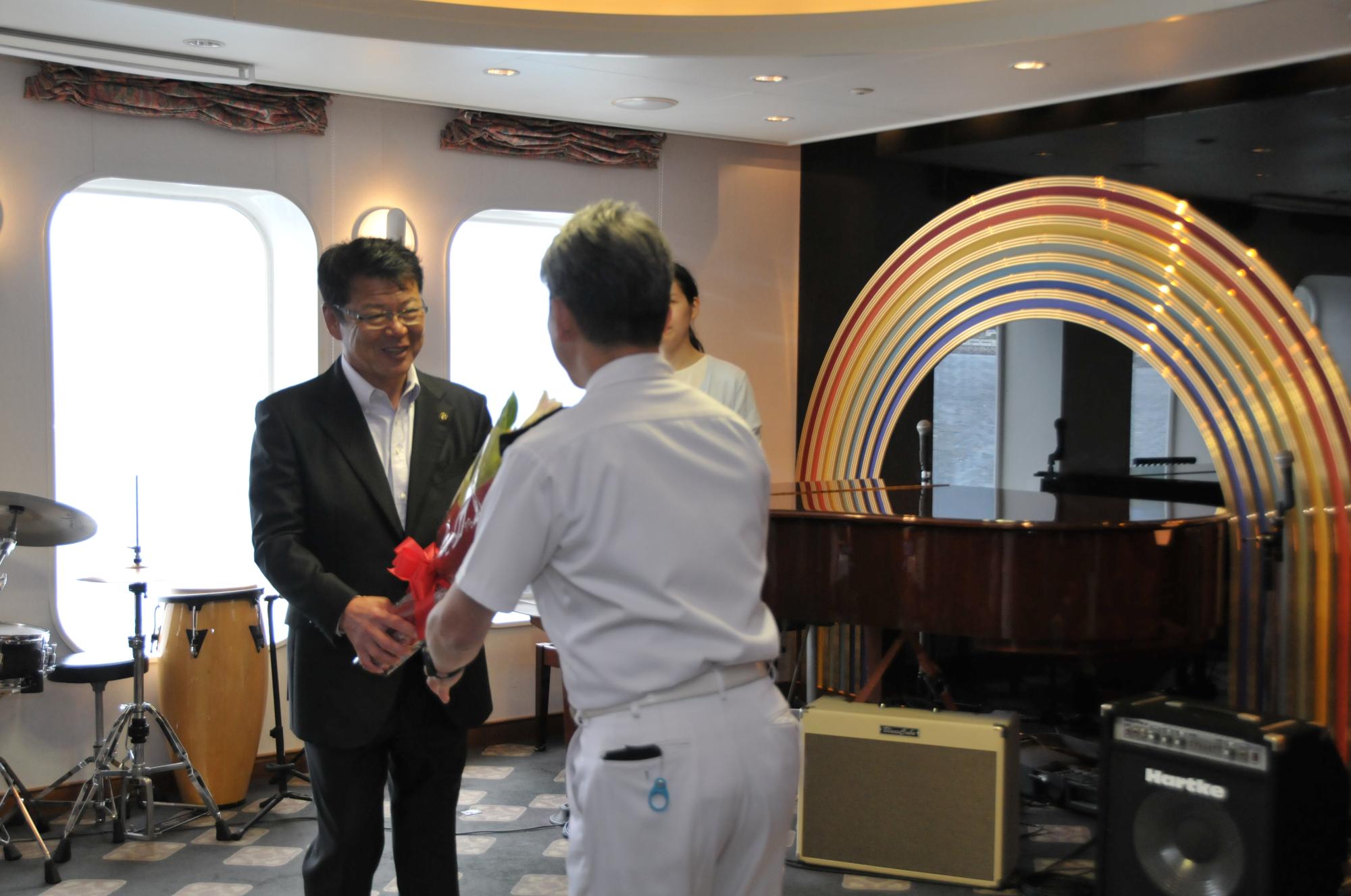 ぱしふぃっくびいなすホテルマネージャーへ歓迎の花束を渡す市長
