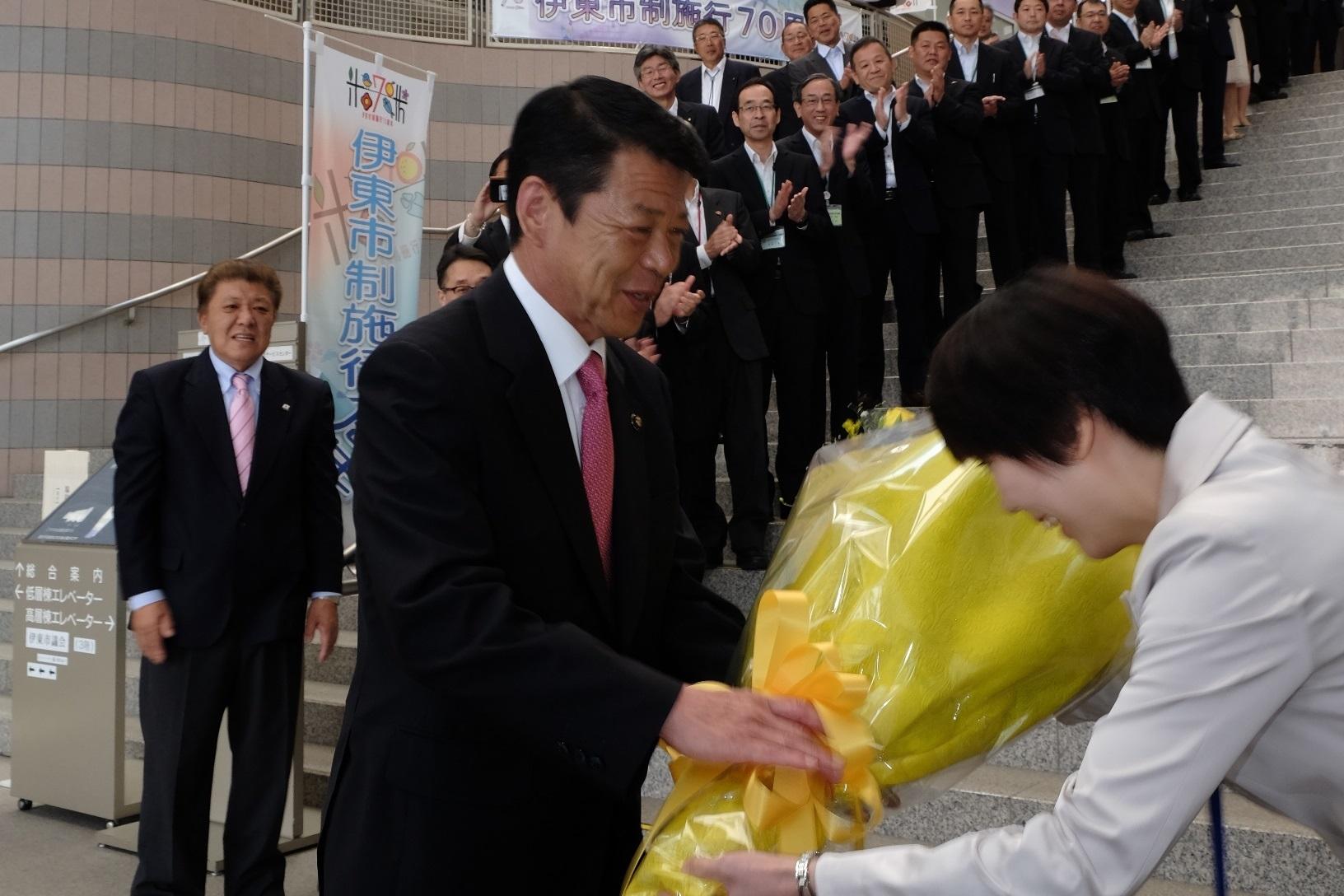 2017年5月29日階段に並び拍手をする市職員の皆さんと女性から花束を受取る市長の写真