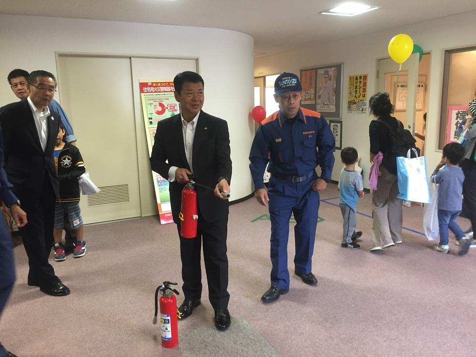伊東消防署で開催された消防フェスタにて消火器を構える伊東市長の写真