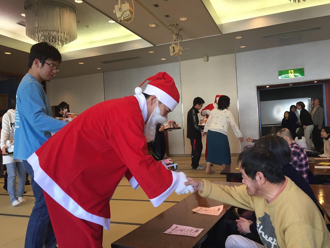 2017年12月17日クリスマス会でプレゼントを配りながら握手をする市長の写真