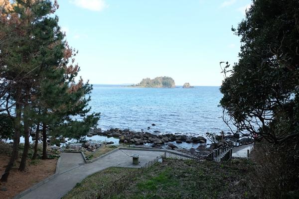 公園の遊歩道と海を挟んだ手石島の写真
