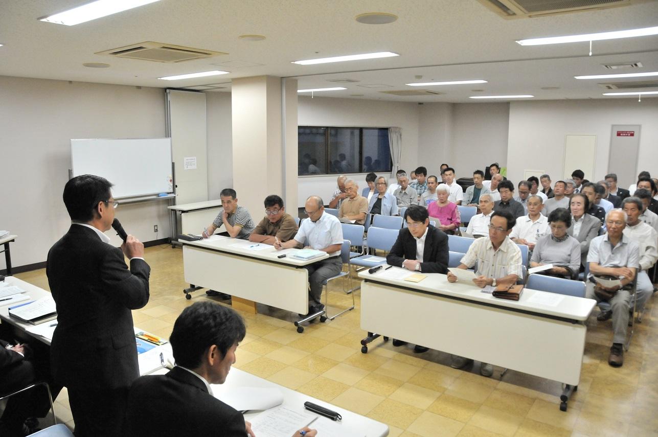 湯川会場の椅子に座り話を聞く参加者とマイクを持ち話をする市長の写真