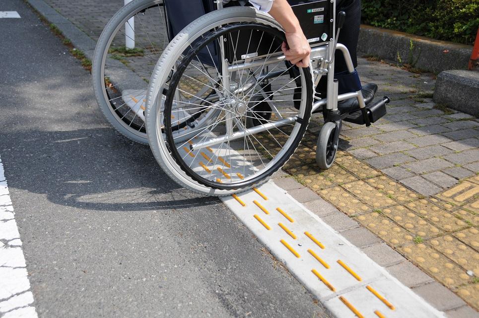 横断歩道と側道の間に施工されたスロープを通る車椅子の写真