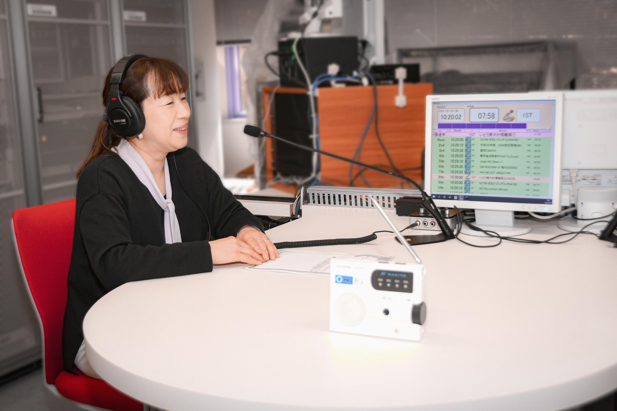 スタジオでラジオ放送をしている女性パーソナリティの写真