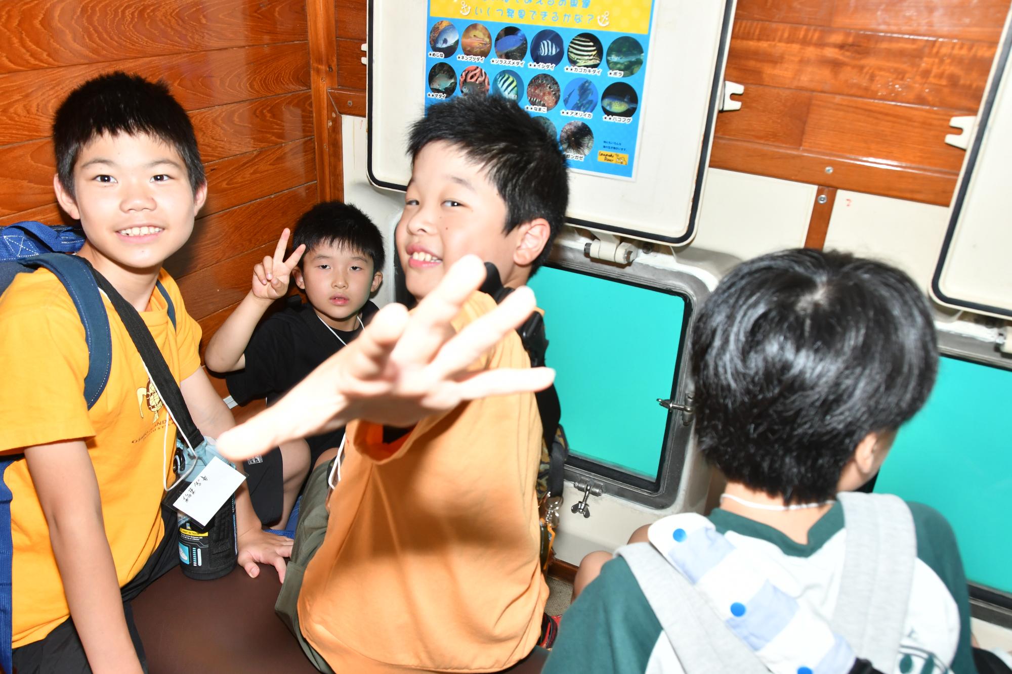遊覧船の中で海中散策を楽しむ子ども達の写真